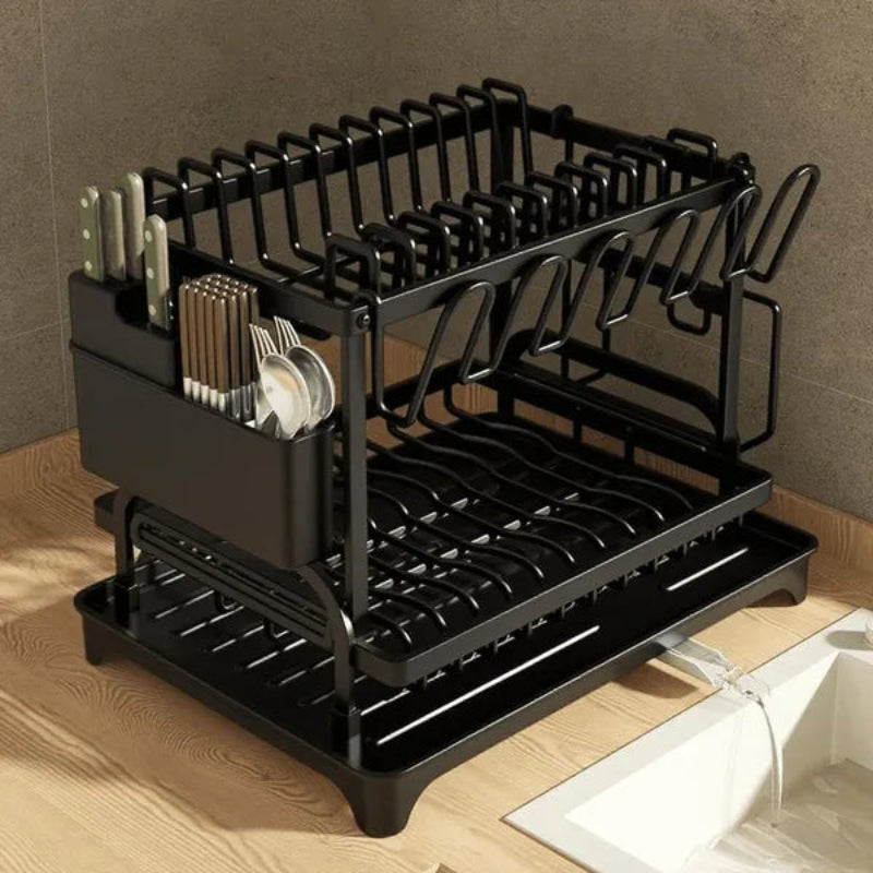 Black dish rack with cutlery and dishes on a wooden countertop.